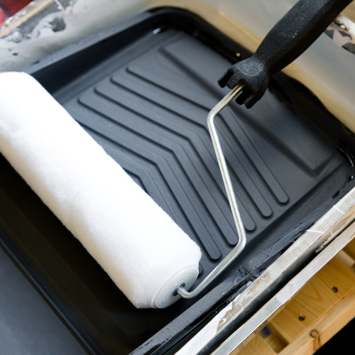 Clean paint roller in a black paint tray